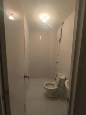 a white bathroom with a toilet and a sink at Yujia Apartment in Manila