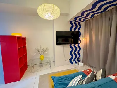 a living room with a couch and a tv at BGC Uptown Parksuites 1BR 14P in Manila