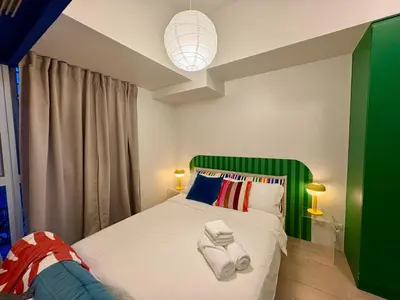 a bedroom with a bed with a green headboard at BGC Uptown Parksuites 1BR 14P in Manila