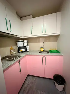 a small kitchen with pink cabinets and a sink at BGC Uptown Parksuites 1BR 14P in Manila