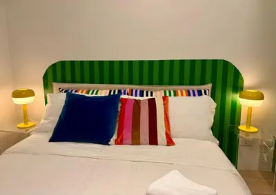 a bed with a green headboard with pillows and two lamps at BGC Uptown Parksuites 1BR 14P in Manila