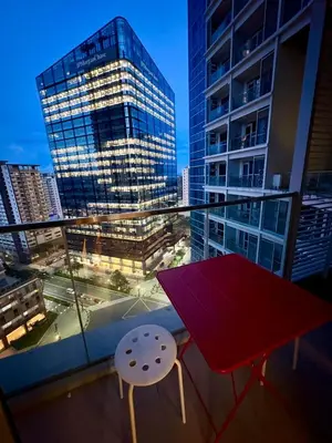 a red table and chair on a balcony with a building at BGC Uptown Parksuites 1BR 14P in Manila