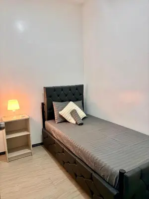 a bed in a room with a lamp on a table at Pasay Transient Rooms in Manila