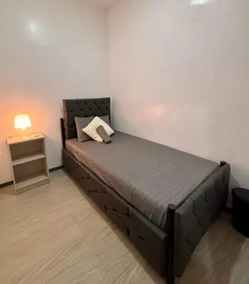 a bed in a room with a side table at Pasay Transient Rooms in Manila
