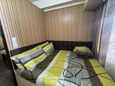 a bedroom with a bed with a yellow and gray comforter at Air Residences 2111k'Pads in Manila