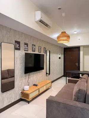 a living room with a couch and a tv on a wall at Cozy Modern- King Bed- City View in Manila