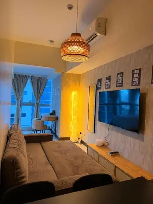 a living room with a large bed and a television at Cozy Modern- King Bed- City View in Manila