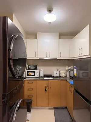 a kitchen with white cabinets and a black refrigerator at Cozy Modern- King Bed- City View in Manila