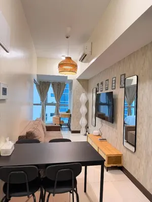 a living room with a couch and a table and a tv at Cozy Modern- King Bed- City View in Manila