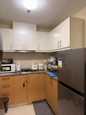 a kitchen with white cabinets and a black refrigerator at Cozy Modern- King Bed- City View in Manila