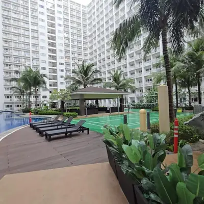 a large apartment building with a swimming pool and benches at Book ME at Shore Residences Tower D near Airport & Mall of Asia in Manila