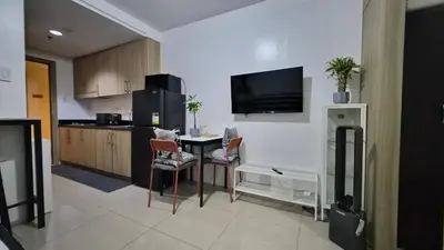 a kitchen with a table and a tv on the wall at Book ME at Shore Residences Tower D near Airport & Mall of Asia in Manila
