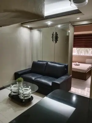 a living room with a black leather couch and a bed at Affordable condotel paranaque in Manila