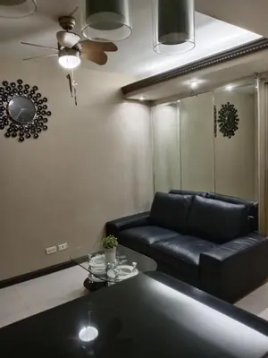 a living room with a black leather couch and a table at Affordable condotel paranaque in Manila