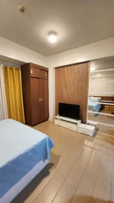 a bedroom with a bed and a flat screen tv at 10P North Wing in Manila