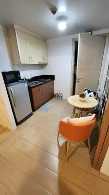 a kitchen with a table and a small table and a chair at 10P North Wing in Manila