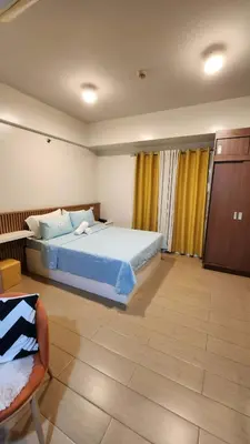 a bedroom with a large bed and a chair at 10P North Wing in Manila