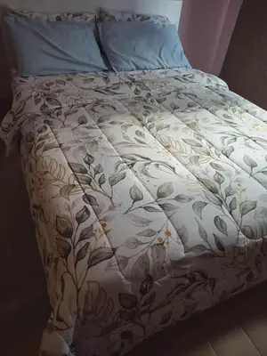 a bed with a white comforter with flowers on it at 4V North Wing in Manila