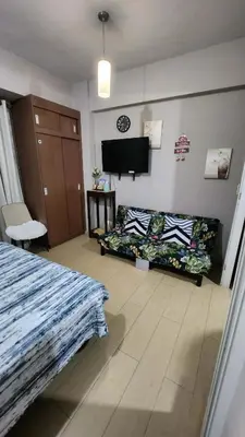 a bedroom with a bed and a couch and a tv at 1OK South Wing in Manila