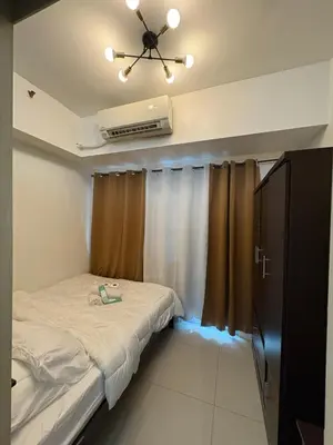 a small room with a bed and a ceiling fan at Condomatch Staycation in Manila