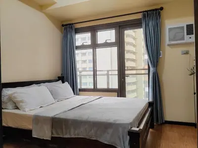 a bedroom with a bed and a large window at Moonsky Suites in Manila