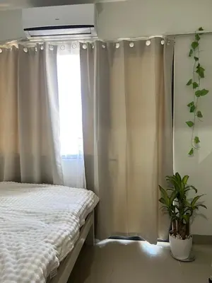 a bedroom with a bed and a window with curtains at Althalia Grandsuites Staycation in Manila
