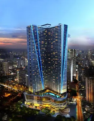 a tall building in a city at night at Relaxing Escape 2 Beds Rattan Chair & 65 inch Smart TV in Manila