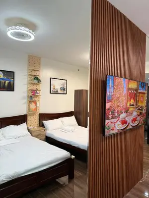 a room with two beds and a christmas picture on the wall at Relaxing Escape 2 Beds Rattan Chair & 65 inch Smart TV in Manila