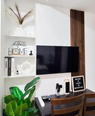 a room with a desk with a tv on a wall at Azure De Joaquin in Manila
