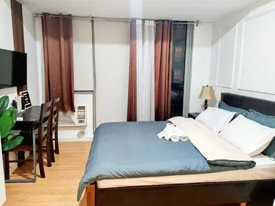 a bedroom with a bed and a desk in it at Azure De Joaquin in Manila