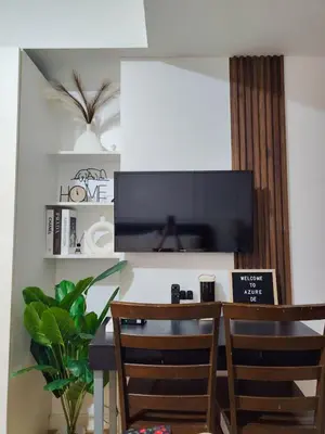 a dining room table with two chairs and a flat screen tv at Azure De Joaquin in Manila