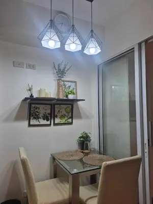 a dining room with a table and chairs and lights at Azure urban residences bicutan parañaque city in Manila