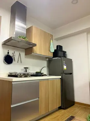 a kitchen with a stainless steel refrigerator and wooden cabinets at Azure Urban Resort Residences by JEs Cabin in Manila