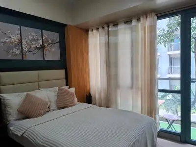 a bedroom with a bed and a large window at Palme d'Or Stay in Manila