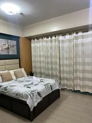 a bedroom with a bed and a window with curtains at Palme d'Or Stay in Manila