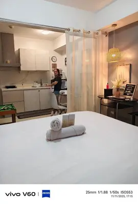 a woman standing in a kitchen with a towel on a bed at The Infinity Staycation in Manila