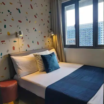 a bed in a room with a wall with a window at 1 Bedroom in S Residences in Manila