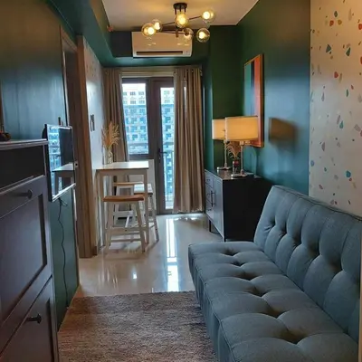 a living room with a blue couch and a kitchen at 1 Bedroom in S Residences in Manila