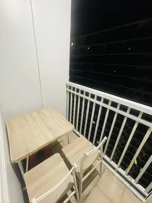 a wooden table and a chair sitting on a balcony at Pasay City-Shore Staycation Ph in Manila