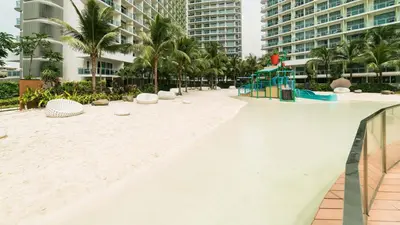 an empty beach in a resort with palm trees and buildings at Miami tower azure staycation in Manila