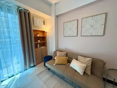 a living room with a couch and a window at Warm & Minimalist 1BR at Two Palm, Newport, T3 in Manila