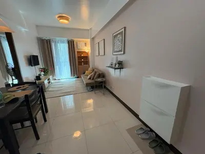 a living room with a table and a refrigerator at Warm & Minimalist 1BR at Two Palm, Newport, T3 in Manila
