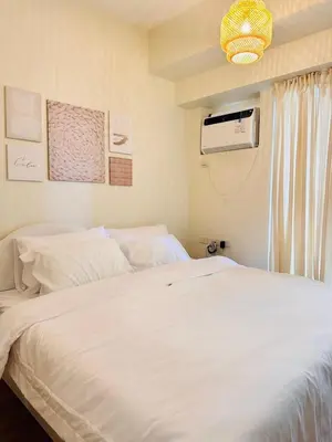 a bedroom with a white bed and a fan at The K-Butter Lounge by Kozy Mood near BGC in Manila