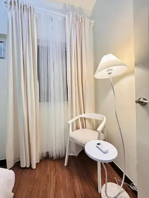 a room with a chair and a lamp and a window at Cloud Cinema by Kozy Mood near BGC in Manila
