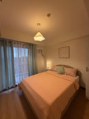 a bedroom with a large bed and a window at Stylish Cozy Nordic 2BR Netflix & Free Parking in Manila