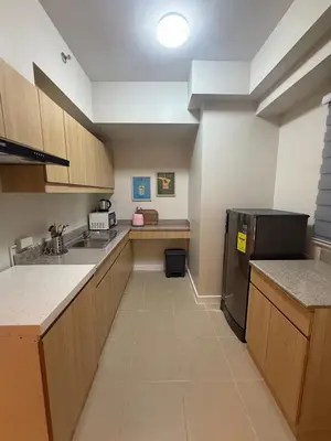 a kitchen with wooden cabinets and a black refrigerator at Stylish Cozy Nordic 2BR Netflix & Free Parking in Manila