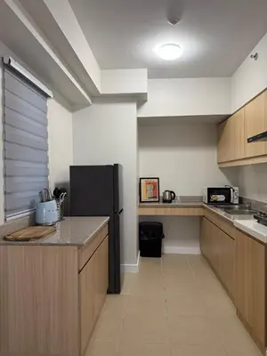 a kitchen with a black refrigerator and wooden cabinets at Spacious 3BR Sucat Netflix and Free Parking in Manila