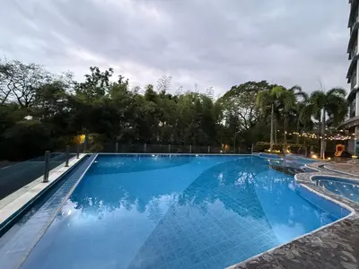 a large swimming pool with blue water at night at Luxurious Taguig Apartment with Private Pool and Central AC in Manila