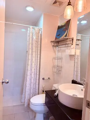 a bathroom with a sink and a toilet and a shower at Luxurious Taguig Apartment with Private Pool and Central AC in Manila