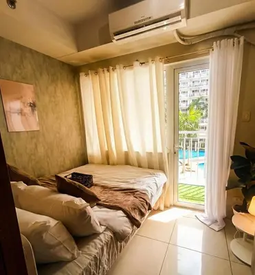 a bedroom with a bed and a large window at Classy Pool view low floor Condo near MoA in Manila
